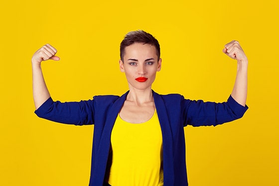 Confident young woman flexing her biceps. Academic coaching and learning a performance skill are exceelent ways to help students build justified self-confidence.